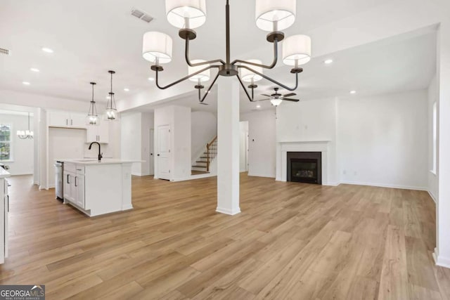 unfurnished living room with ceiling fan, sink, and light hardwood / wood-style flooring