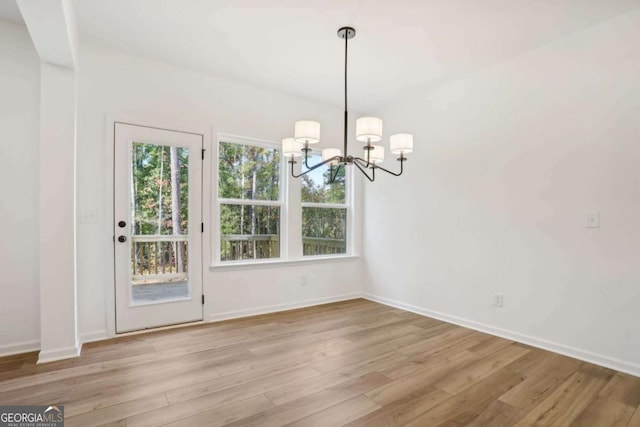 unfurnished dining area featuring light wood-type flooring and a notable chandelier