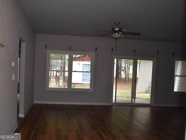 unfurnished room featuring ceiling fan, a healthy amount of sunlight, and dark wood-type flooring