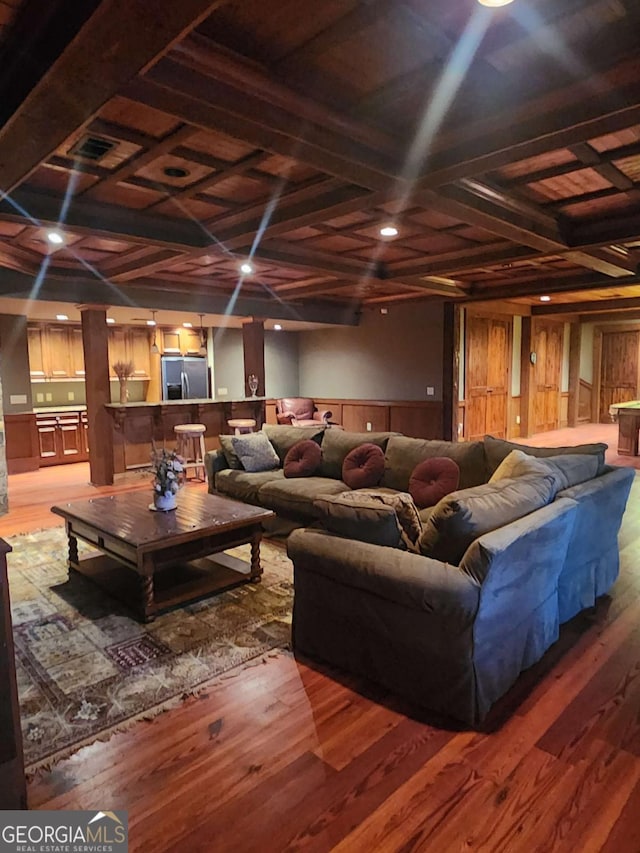 living room featuring hardwood / wood-style floors, wooden walls, and coffered ceiling