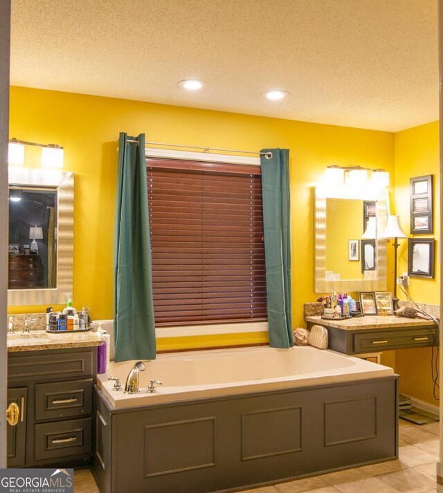 bathroom featuring tile patterned flooring, vanity, a textured ceiling, and a tub