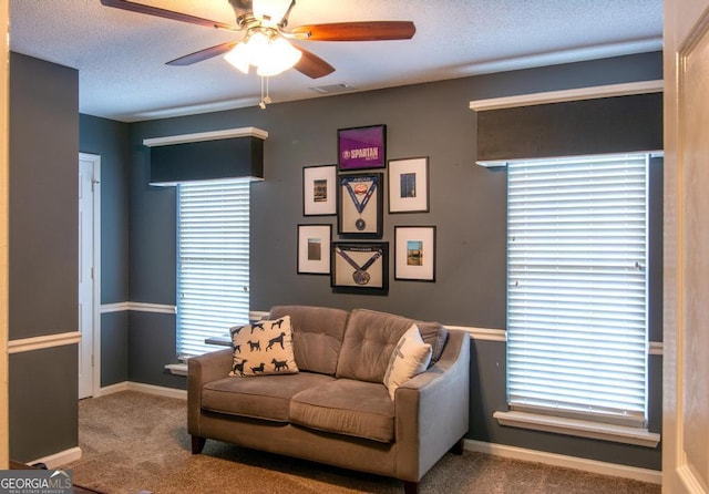 carpeted living room with ceiling fan and a textured ceiling