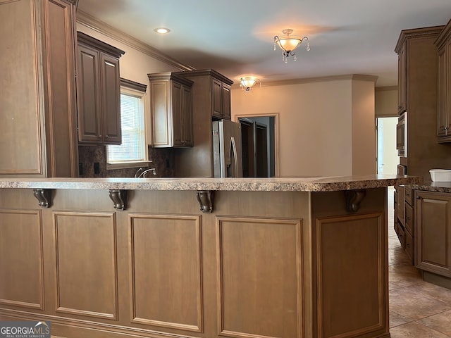 kitchen with a breakfast bar area, decorative backsplash, crown molding, and appliances with stainless steel finishes