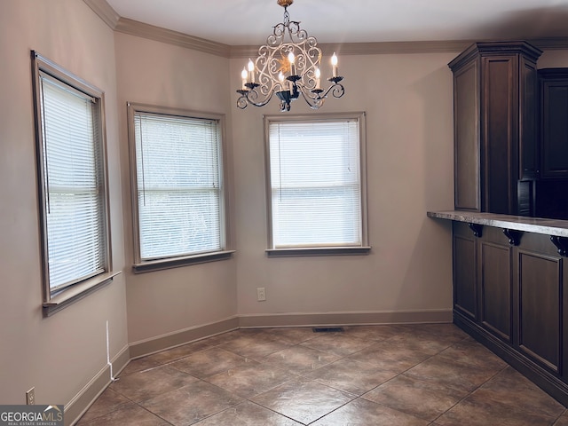 unfurnished dining area featuring a chandelier, dark tile patterned floors, and ornamental molding