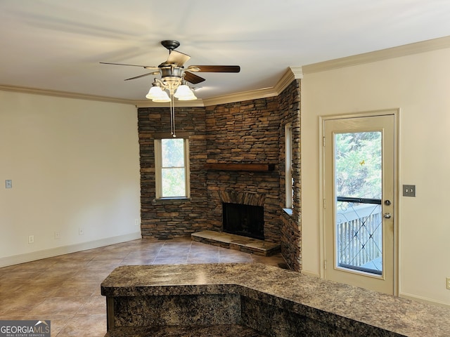 unfurnished living room featuring ceiling fan, a stone fireplace, plenty of natural light, and crown molding