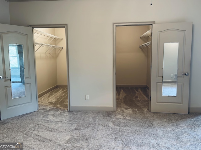 unfurnished bedroom with a walk in closet, a closet, and carpet