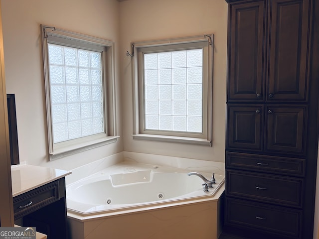 bathroom featuring vanity, a healthy amount of sunlight, and a tub