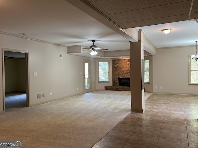 unfurnished living room with carpet floors, a brick fireplace, ceiling fan, and crown molding