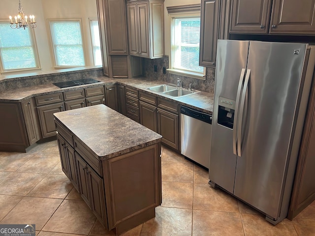 kitchen featuring sink, stainless steel appliances, a chandelier, pendant lighting, and a kitchen island