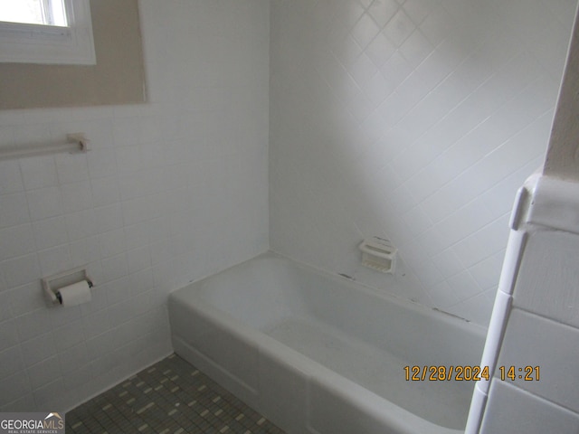 bathroom with tile patterned floors, a bathing tub, and tile walls