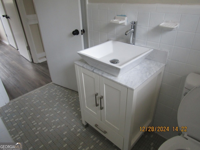 bathroom with tile patterned flooring, vanity, tile walls, and toilet