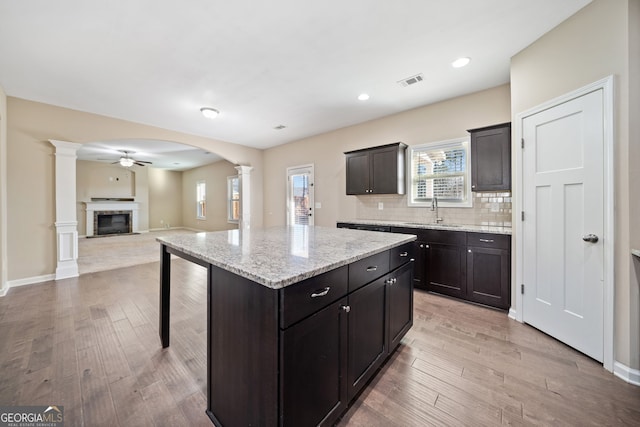 kitchen with ornate columns, a kitchen bar, tasteful backsplash, sink, and a kitchen island