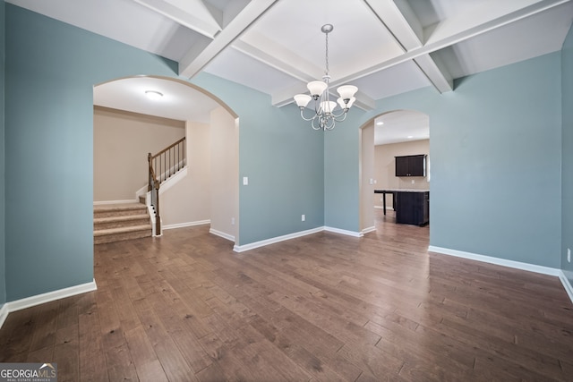 interior space with a notable chandelier, coffered ceiling, beamed ceiling, and dark hardwood / wood-style floors