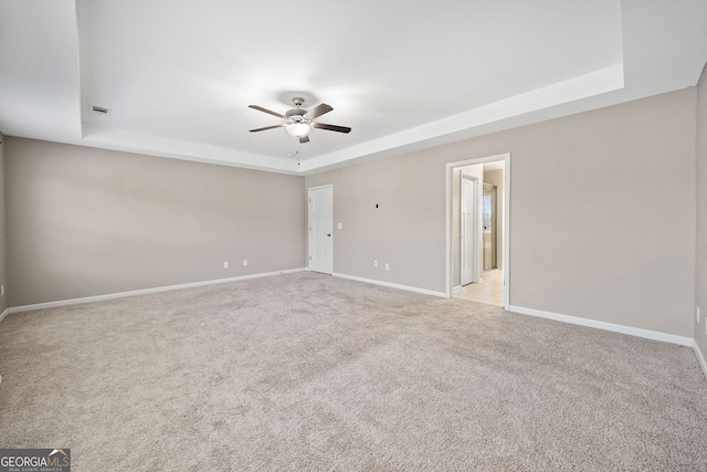 carpeted empty room with ceiling fan and a tray ceiling