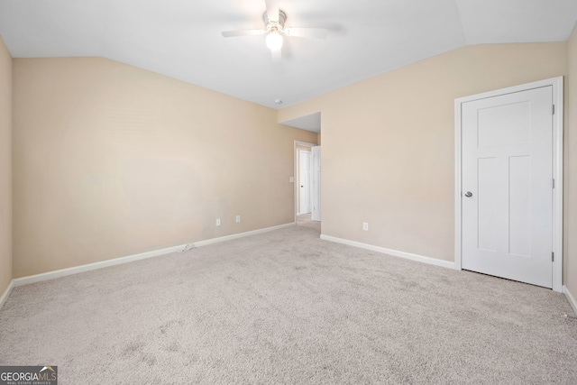 spare room with light colored carpet, vaulted ceiling, and ceiling fan