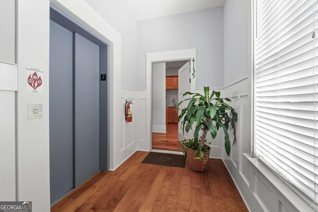 hall with elevator, sink, and dark wood-type flooring