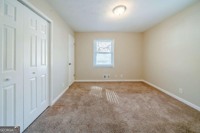 unfurnished bedroom featuring a closet and light colored carpet