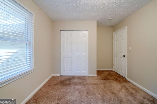 unfurnished bedroom with light colored carpet, a textured ceiling, and a closet