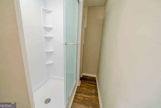 bathroom featuring a shower with shower door and wood-type flooring