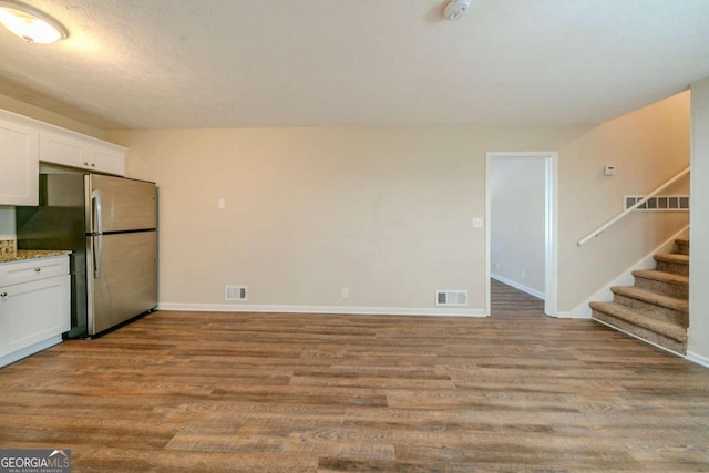 kitchen with stainless steel fridge, white cabinetry, and light wood-type flooring