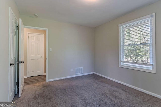 spare room with dark colored carpet