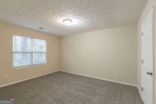 unfurnished room featuring dark colored carpet and a textured ceiling