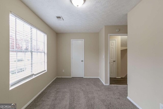 unfurnished room with a textured ceiling and light colored carpet