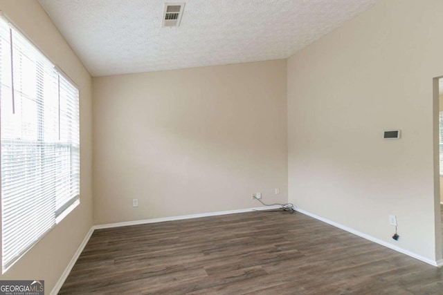 spare room featuring a textured ceiling and dark hardwood / wood-style floors