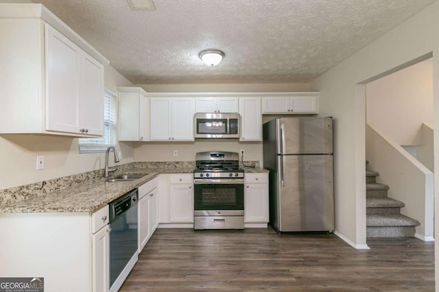 kitchen featuring light stone counters, stainless steel appliances, white cabinetry, and sink