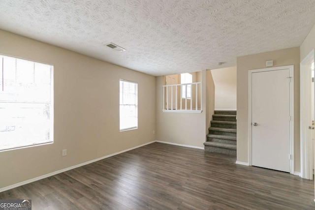 unfurnished room with a wealth of natural light, dark hardwood / wood-style floors, and a textured ceiling