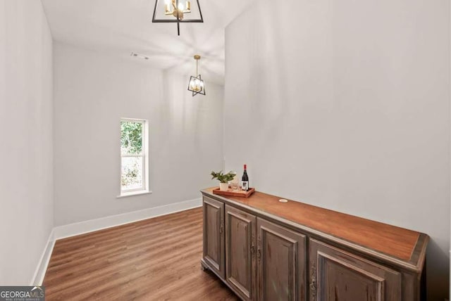 corridor featuring wood-type flooring and a chandelier