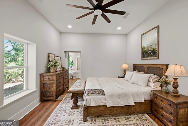 bedroom featuring ceiling fan, wood-type flooring, and a fireplace