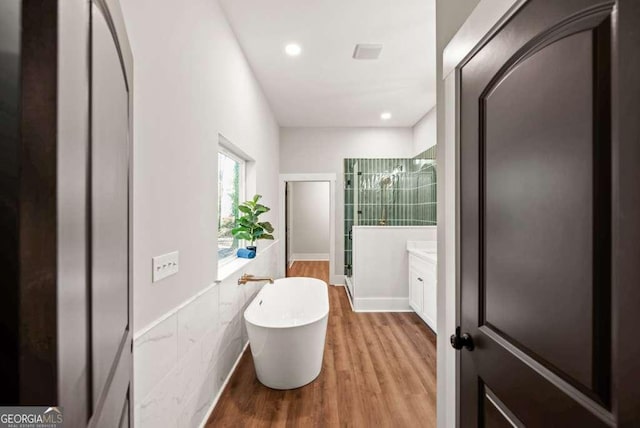 bathroom featuring hardwood / wood-style flooring, vanity, and a tub to relax in