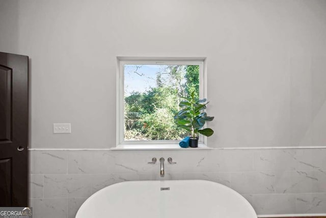 bathroom with a bathing tub and tile walls