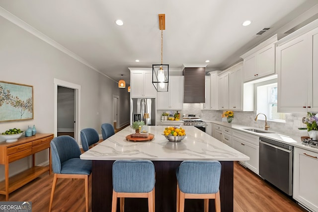 kitchen with a breakfast bar, sink, decorative light fixtures, a kitchen island, and stainless steel appliances