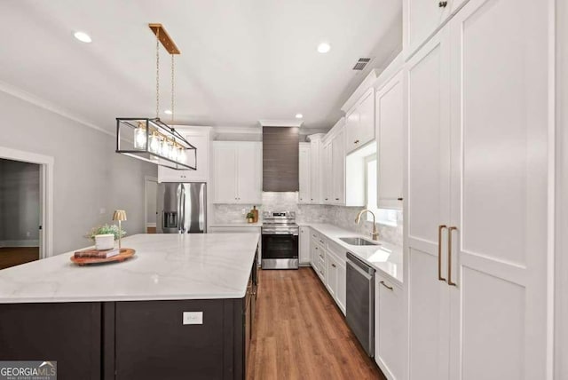 kitchen featuring a kitchen island, pendant lighting, white cabinets, and appliances with stainless steel finishes