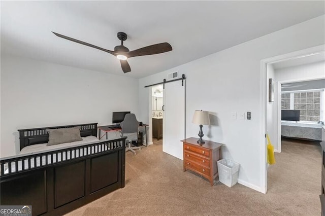 carpeted bedroom with ceiling fan and a barn door