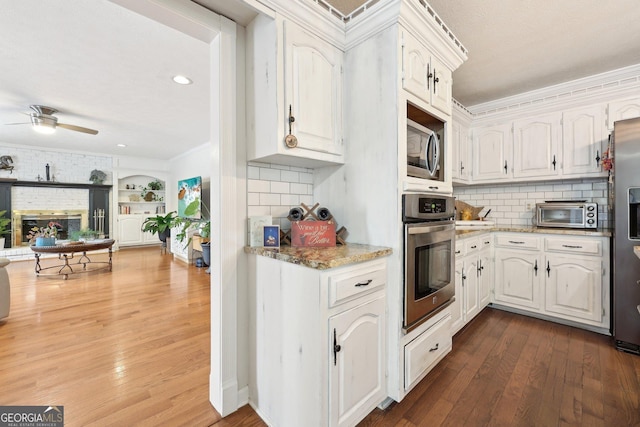 kitchen with decorative backsplash, white cabinets, stainless steel appliances, and dark hardwood / wood-style floors