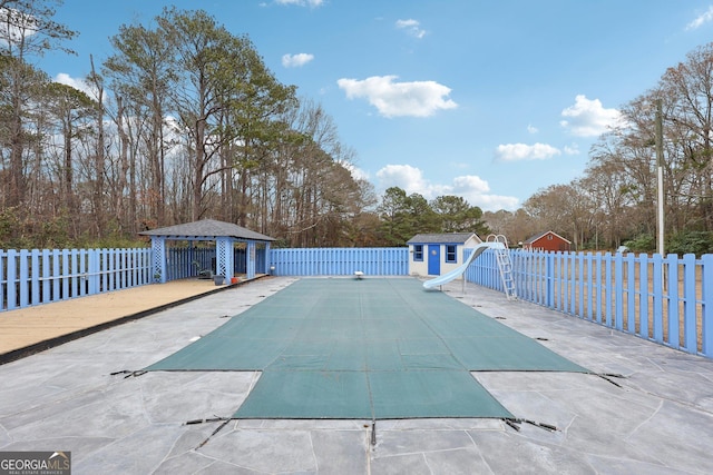 view of swimming pool with a water slide and a storage unit