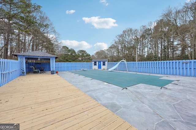 view of swimming pool featuring a patio area, a water slide, and a storage unit