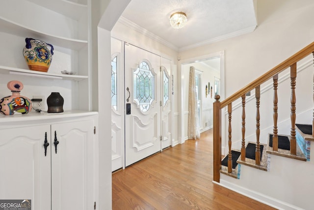 entryway featuring a textured ceiling, crown molding, and light hardwood / wood-style flooring