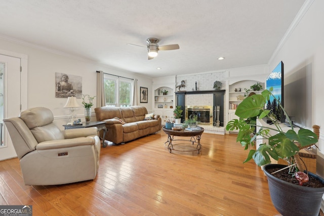 living room with a brick fireplace, a textured ceiling, ceiling fan, light hardwood / wood-style flooring, and built in features