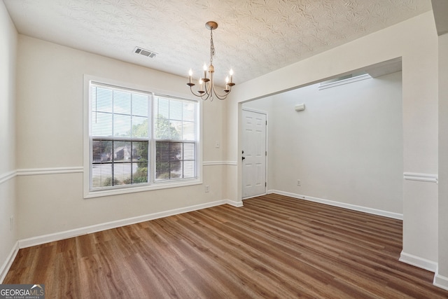 spare room with dark hardwood / wood-style flooring, a chandelier, and a textured ceiling