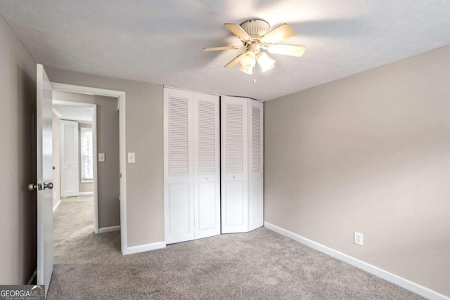 unfurnished bedroom featuring ceiling fan, a closet, and light colored carpet