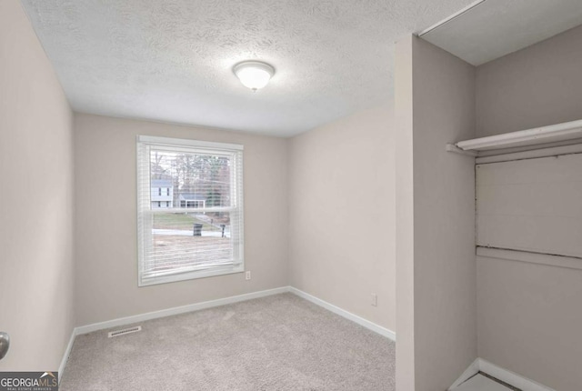 empty room featuring a textured ceiling and light carpet