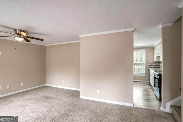 unfurnished living room featuring light carpet, a textured ceiling, ceiling fan, and crown molding