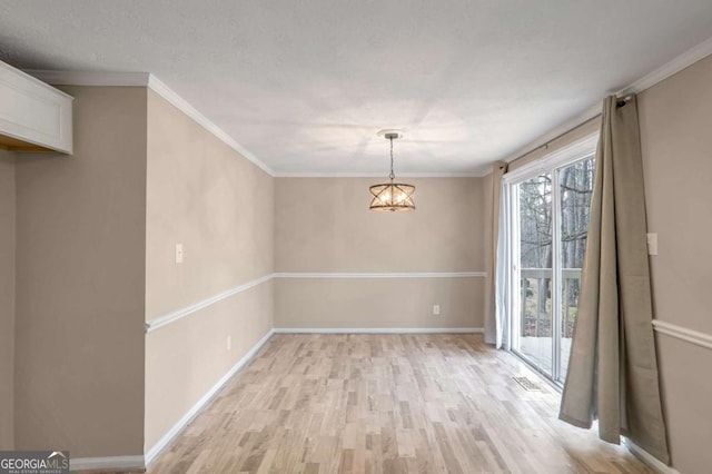 unfurnished dining area featuring an inviting chandelier, light hardwood / wood-style floors, and ornamental molding