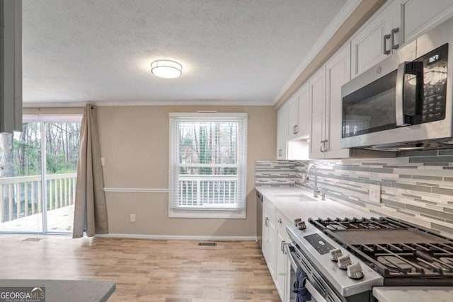 kitchen featuring stainless steel appliances, white cabinetry, tasteful backsplash, and sink