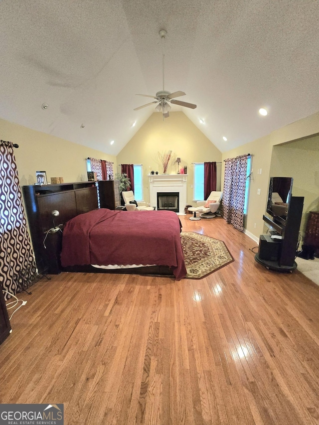 bedroom with ceiling fan, lofted ceiling, a textured ceiling, and light hardwood / wood-style flooring