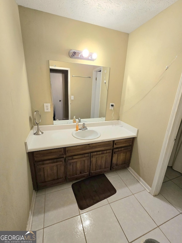 bathroom featuring tile patterned flooring, vanity, and a textured ceiling